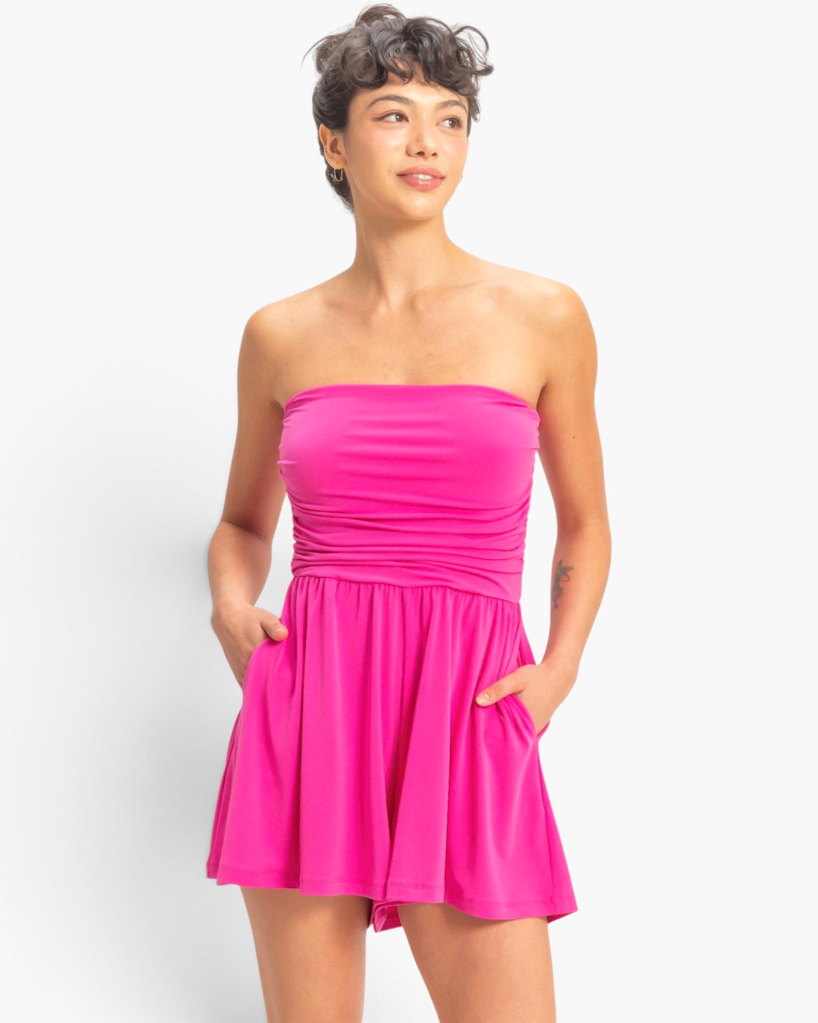 Beach Rose Co. hot pink strapless romper with shirred waist and side pockets worn by a model against a white background