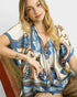 Beach Rose Co. ivory and blue paisley border print rayon top with tassel tie details and short sleeves.