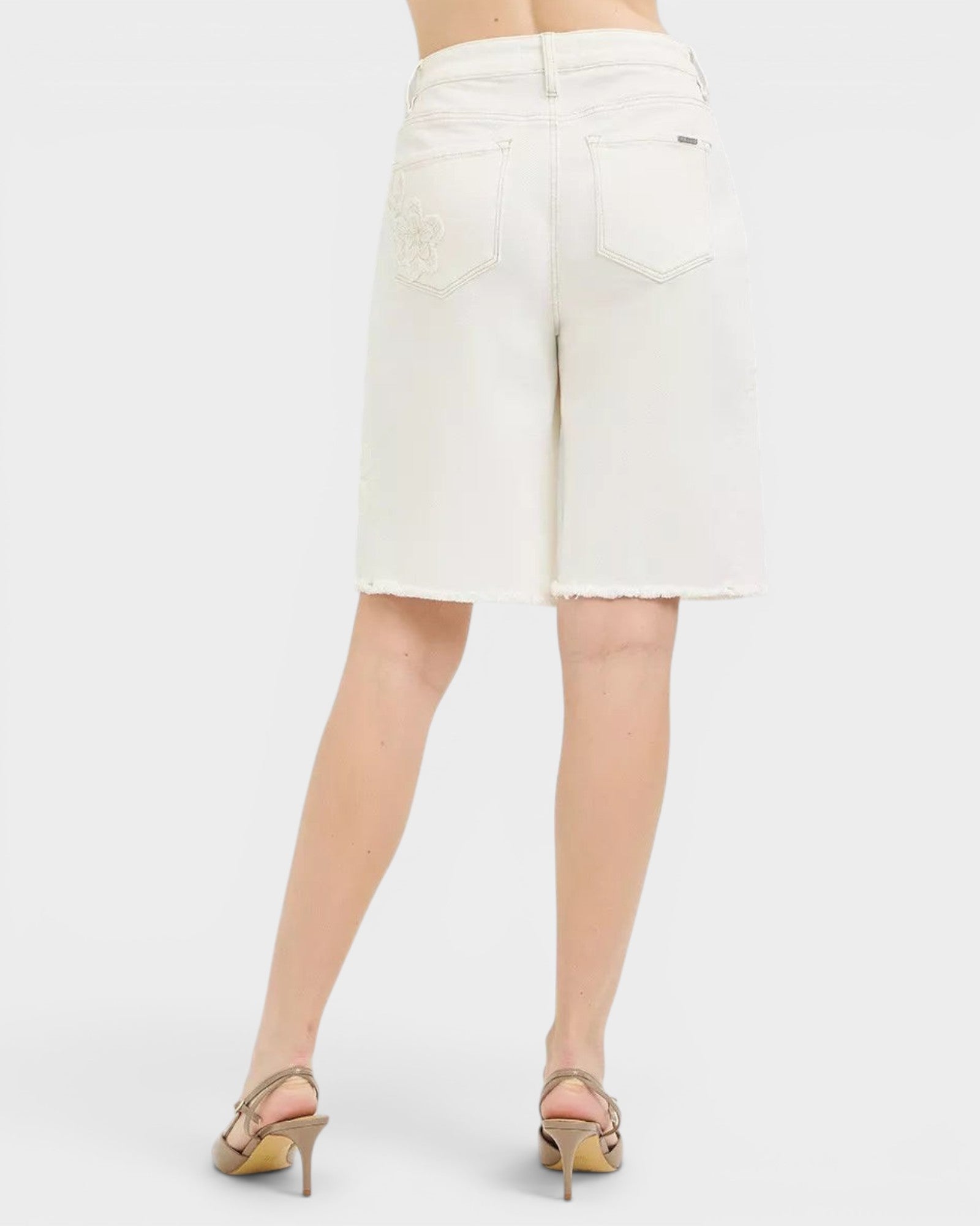 Beach Rose Co. ivory denim Bermuda shorts with tone-on-tone floral embroidery and raw hem. Made of cotton and spandex.