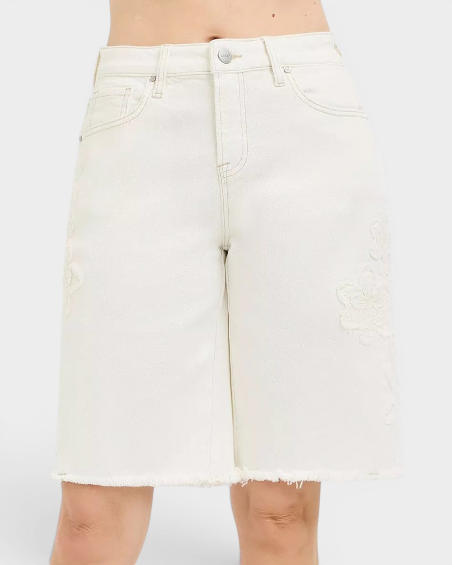Beach Rose Co. Ivory denim Bermuda shorts with tone-on-tone floral embroidery and raw hem. Made of 98% cotton, 2% spandex.