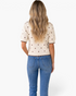 Back view of a Beach Rose Co. ivory cotton knit top with brown polka dots, puff sleeves, and scalloped trim.
