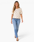 Beach Rose Co. ivory cotton knit top with brown polka dots, puff sleeves, and scalloped trim worn with blue jeans.