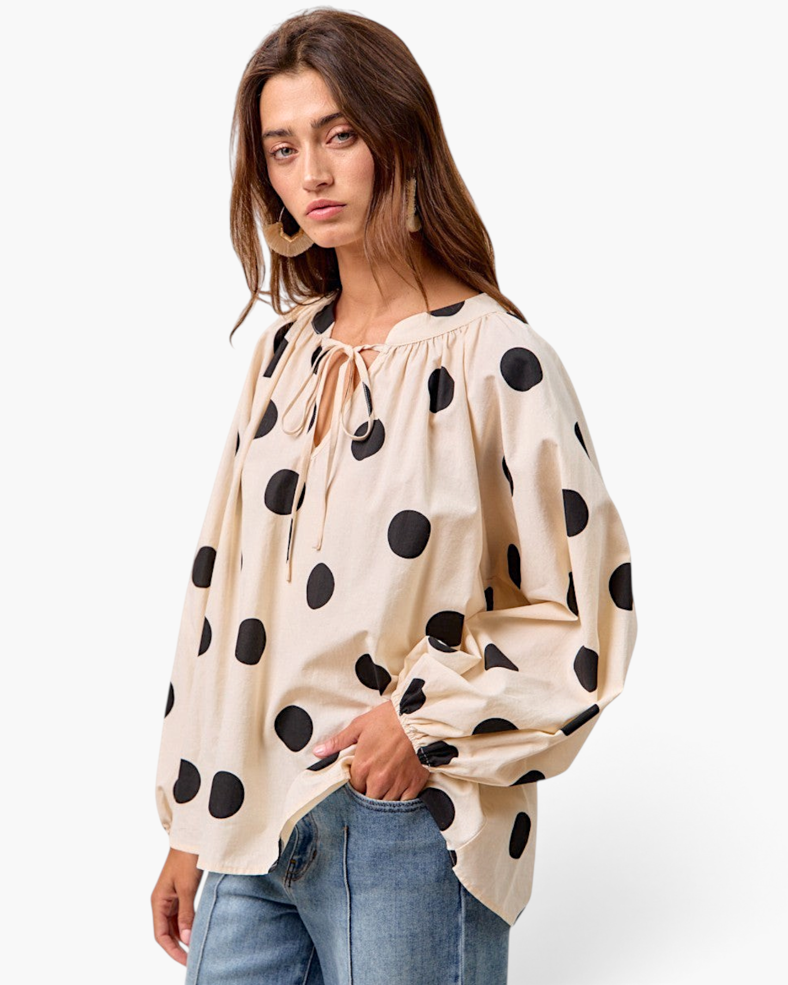 Model wearing a Beach Rose Co. ivory cotton top with black polka dots, tie-neck, and long balloon sleeves.