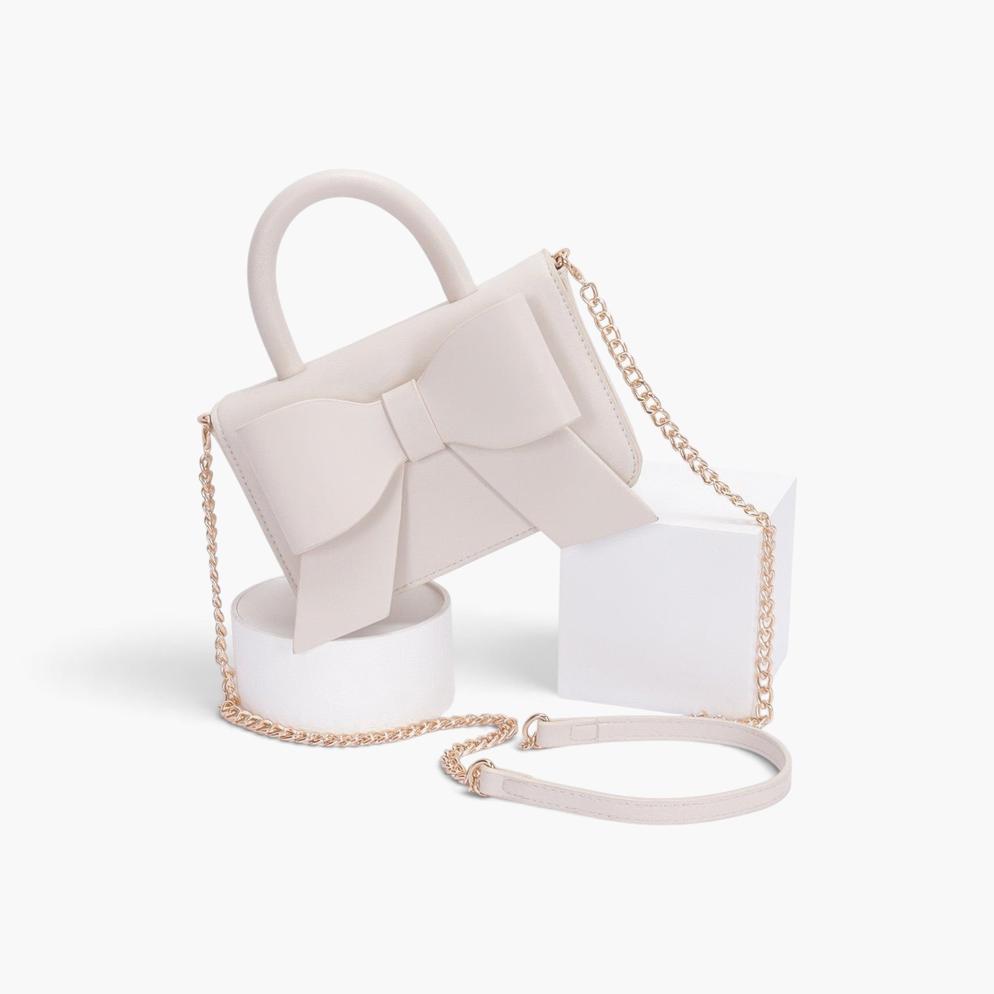 Beach Rose Co. ivory faux leather handbag with a ribbon bow detail, top handle, and gold chain shoulder strap.