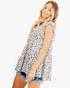 Beach Rose Co. ivory tiered flutter sleeve top with black spotted print worn by a smiling woman with denim shorts