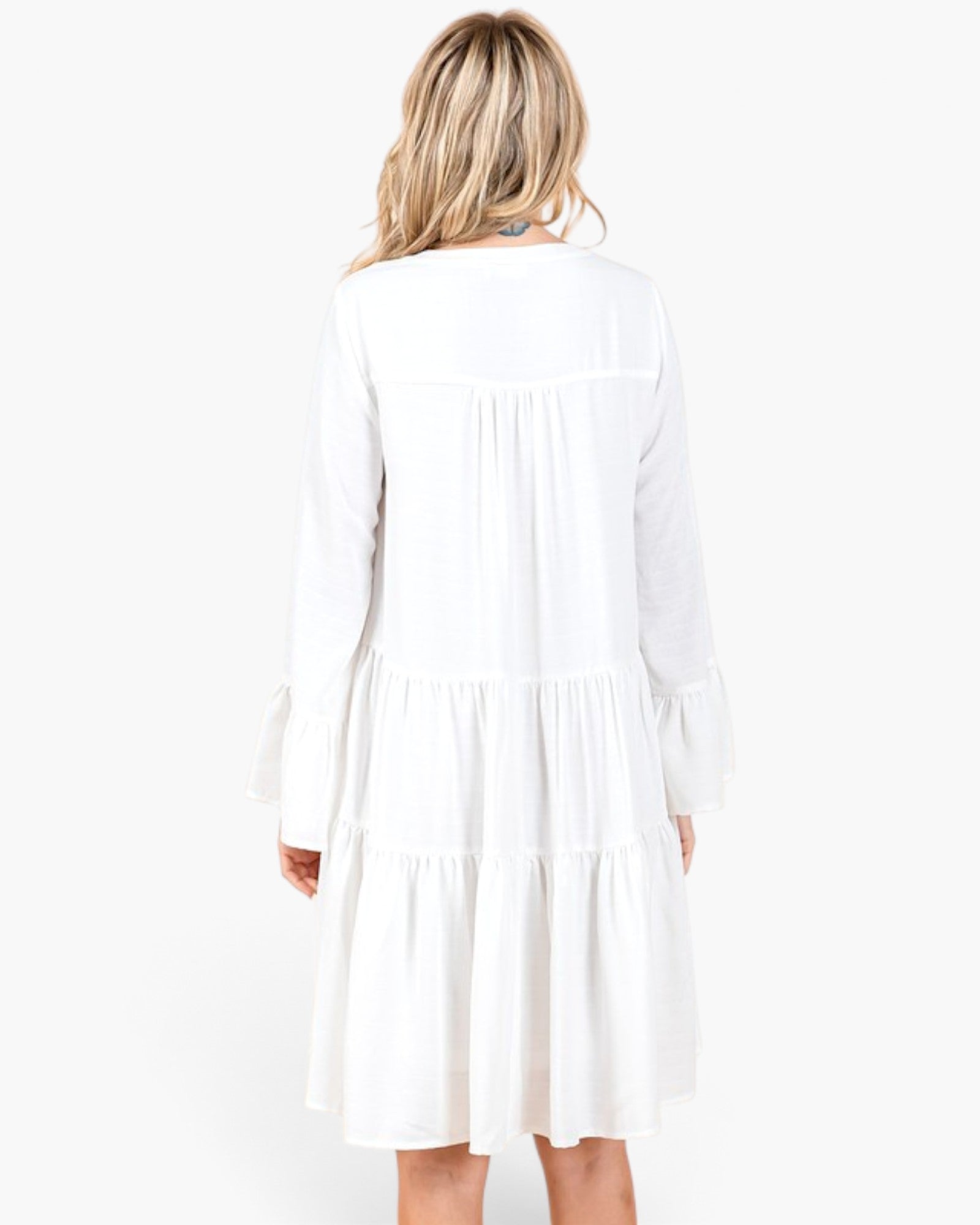 Back view of Beach Rose Co. ivory tiered shift dress with long bell sleeves and gathered detailing on white background