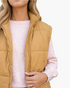 Beach Rose Co. khaki quilted puffer vest with a stand collar and full zip front worn over a light pink sweater.
