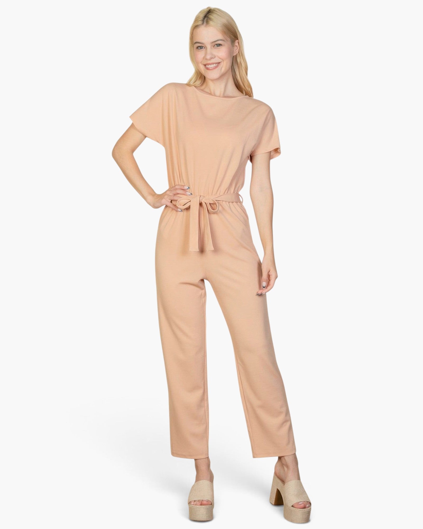 Beach Rose Co. model wearing a khaki relaxed rib knit jumpsuit with a tie waist and short sleeves on white background