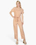 Beach Rose Co. model wearing a khaki relaxed rib knit jumpsuit with a tie waist and short sleeves on white background