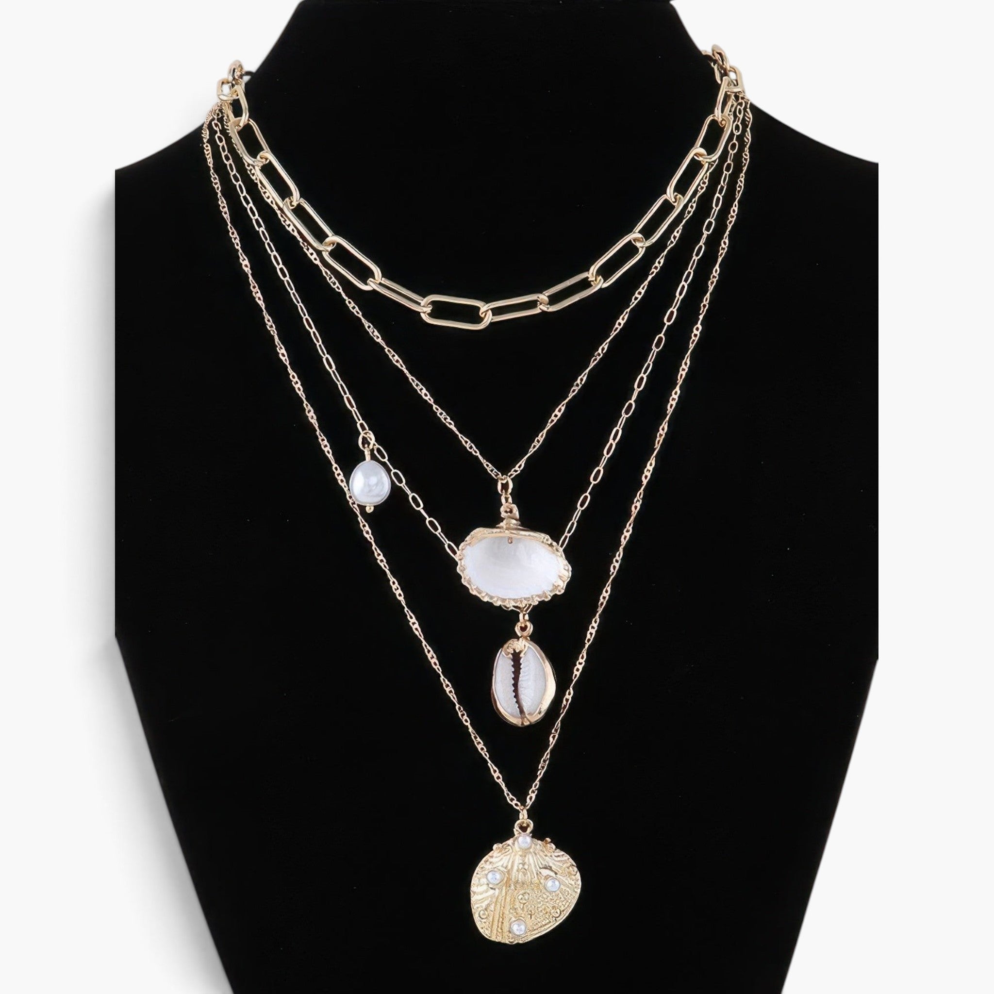 Beach Rose Co. layered gold chain necklace featuring seashell, starfish, and pearl charms on a black display bust.