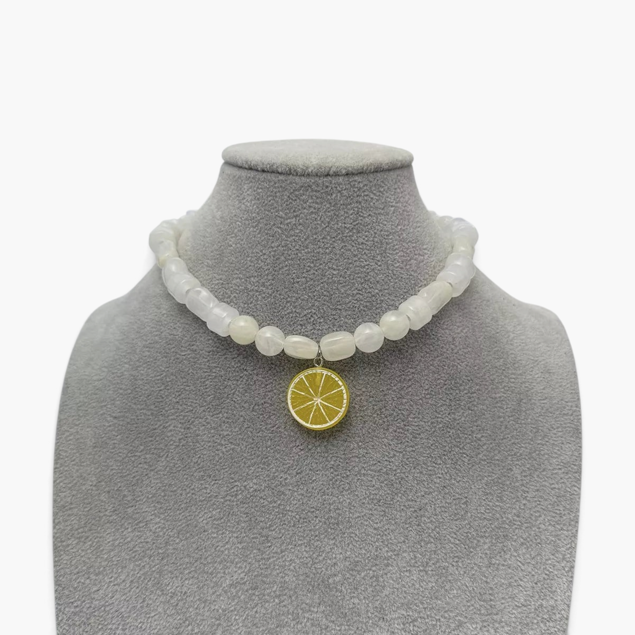 Beach Rose Co. white resin beaded necklace featuring a yellow lemon slice pendant on a grey jewelry display bust.