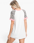 Beach Rose Co. ivory top with leopard-print raglan sleeves and pink trim, viewed from the back on a model.
