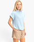 Beach Rose Co. light blue cotton button-up top with rolled sleeves and chest pocket worn by a smiling blonde model