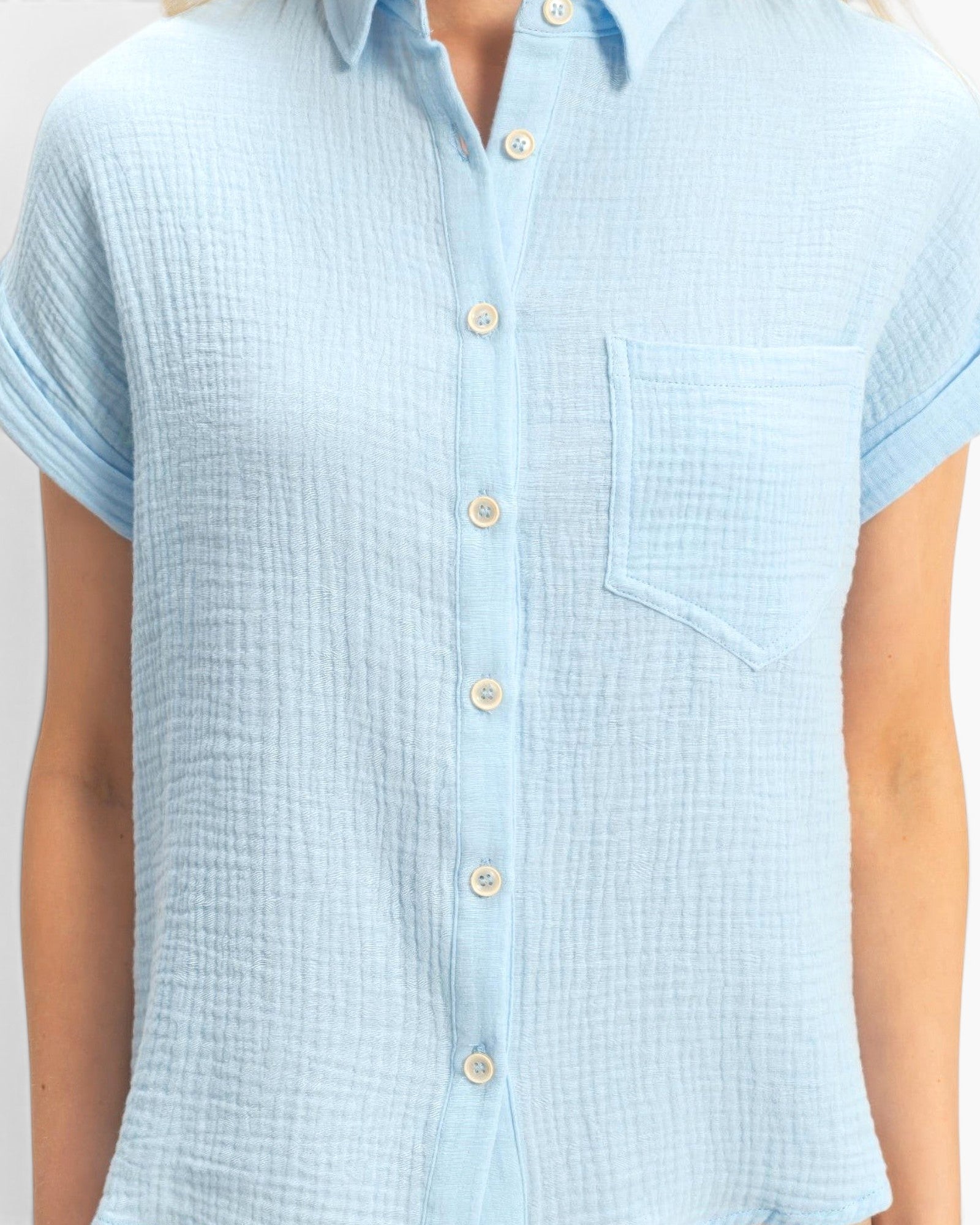 Beach Rose Co. light blue cotton button-up top with rolled sleeves and a single chest pocket on a model