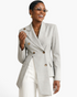 Beach Rose Co. light gray asymmetrical double-breasted blazer with notched lapels worn by a smiling woman.