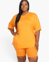 Beach Rose Co. plus size mango orange loose fit top and biker shorts set worn by a model on a white background.