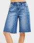 Beach Rose Co. medium wash denim Bermuda shorts with raw hem, five-pocket styling, and stretch fabric.