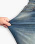 Beach Rose Co. medium wash denim jeans being stretched to show the fabric elasticity and texture