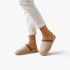 Beach Rose Co. Melanie beige suede slippers with plush lining and decorative trim worn on feet with white trousers