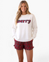 Beach Rose Co. white long sleeve lounge top with merry graphic and red plaid ruffle shorts worn by a smiling woman.