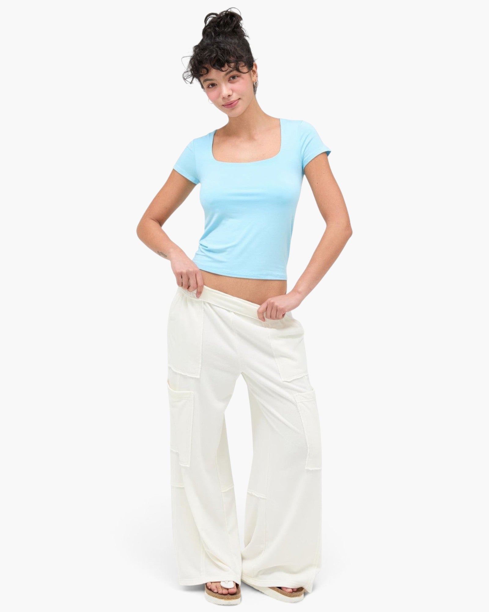 Model wearing Beach Rose Co. mineral wash wide leg cargo pants with raw edge pockets and a light blue crop top