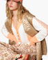 Beach Rose Co. mocha floral quilted zip-up vest worn over a white and peach long-sleeve top with patterned pants.