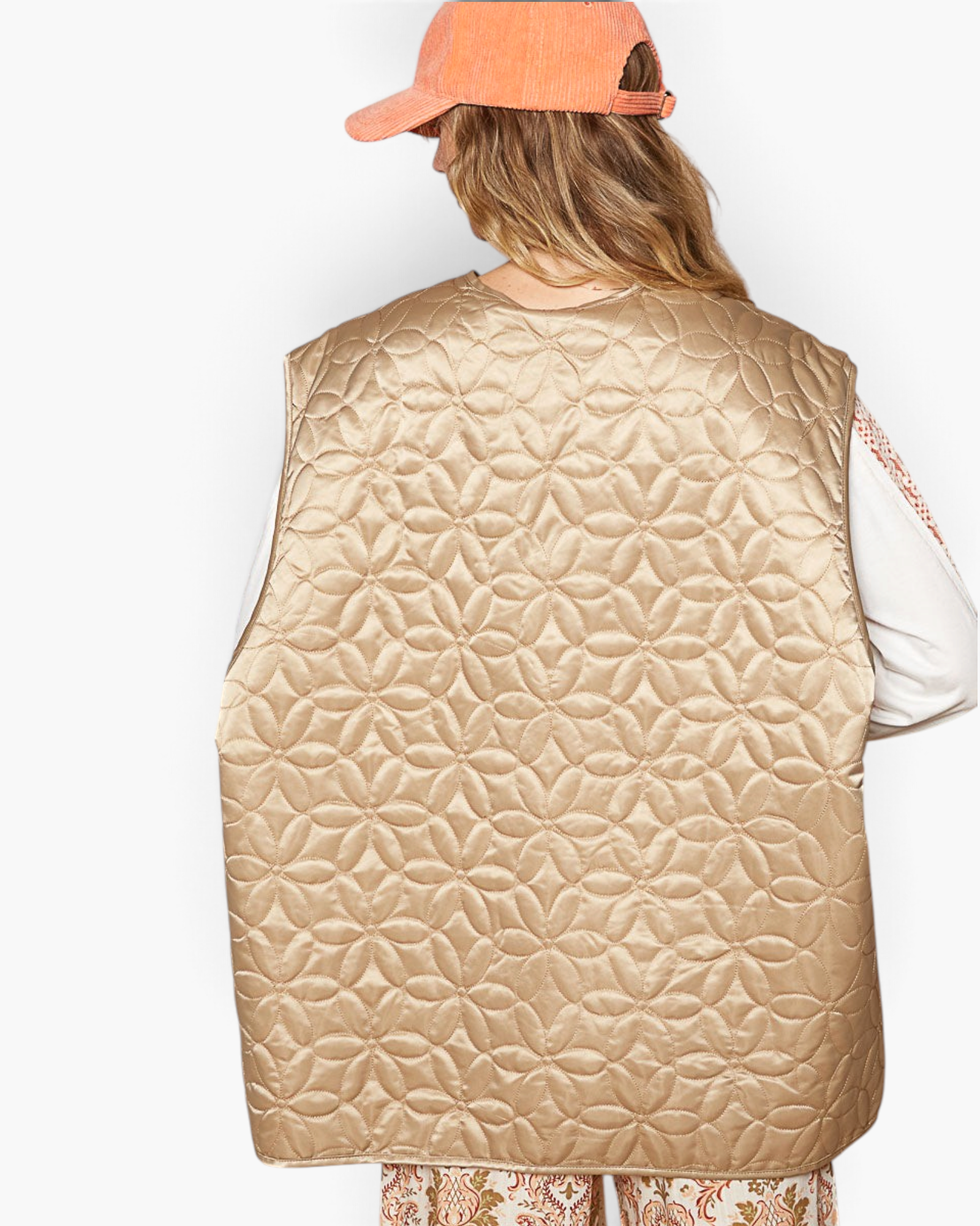 Beach Rose Co. mocha floral quilted nylon vest with a subtle sheen worn by a model in a peach corduroy baseball cap.