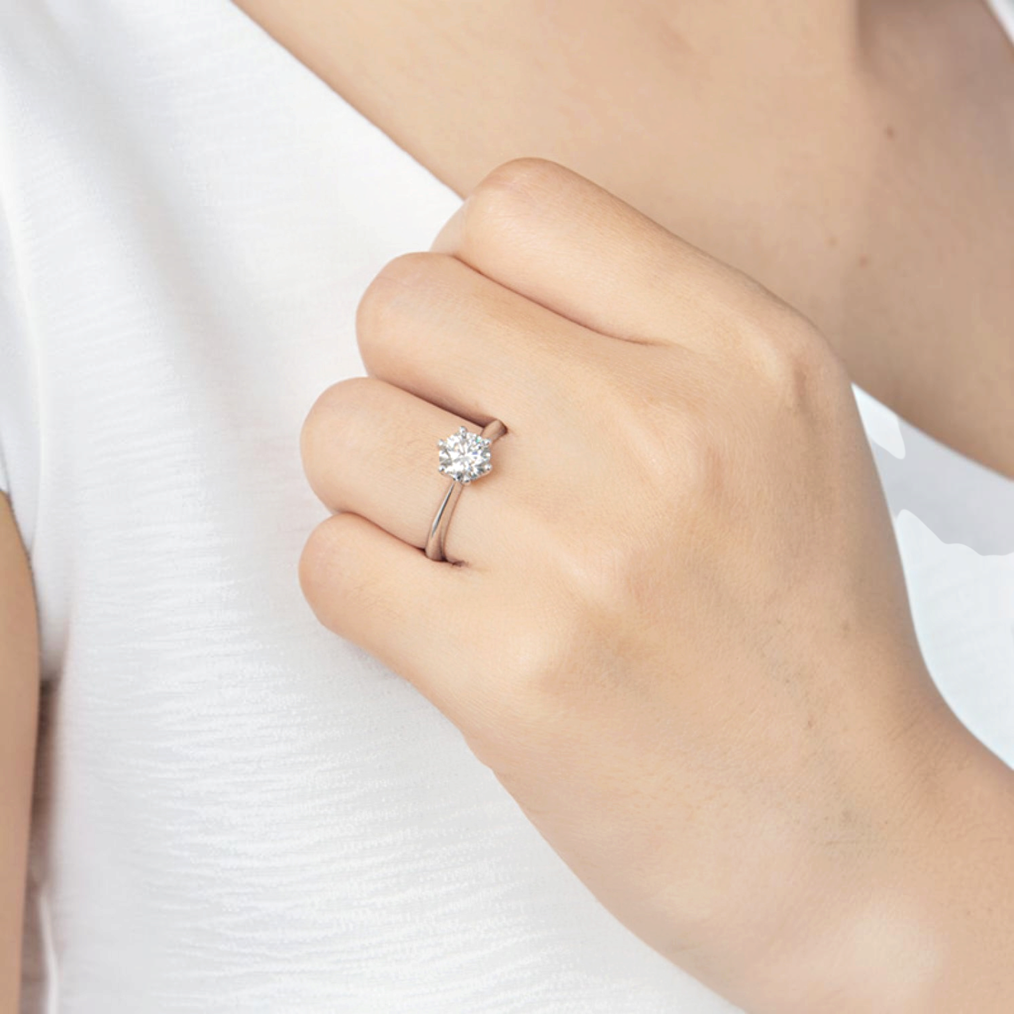 Beach Rose Co. 1 carat round moissanite solitaire ring in platinum-plated sterling silver on a woman's hand.