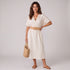 Beach Rose Co. multicolor woven belt with gold bamboo-style buckle worn by a woman in a white dress