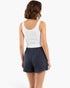 Woman wearing Beach Rose Co. navy blue cotton comfort shorts and a white ribbed tank top, back view