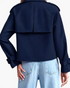 Back view of Beach Rose Co. navy blue cropped trench jacket with storm flap and buckled cuffs worn with light jeans.