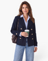 Beach Rose Co. navy double-breasted jacket with gold buttons and notched lapels worn by a woman with a coffee cup.