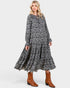 Beach Rose Co. navy floral maxi dress with long sleeves, tie neckline, and tiered skirt, styled with brown boots.