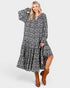Beach Rose Co. navy floral maxi dress with long sleeves, tie neckline, and tiered skirt worn with brown ankle boots.