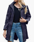 Beach Rose Co. navy blue waterproof hooded rain jacket with zip front, flap pockets, and gathered waist on a model.