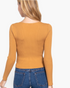 Beach Rose Co. ochre ribbed long-sleeve sweater top with a fitted silhouette worn by a model from the back view.