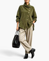 Beach Rose Co. olive green corduroy jacket with asymmetrical buttons and foldover collar worn with beige trousers.
