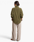 Beach Rose Co. olive corduroy jacket with a back vent and relaxed fit worn with beige trousers, rear view.