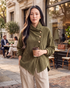 Beach Rose Co. olive green corduroy jacket with asymmetrical buttons and foldover collar worn by a woman outdoors.