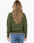 Beach Rose Co. olive green knit sweater with gingham ruffle trim at the hem and cuffs, worn with blue jeans.