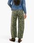 Beach Rose Co. olive green barrel leg jeans with paisley print, back view on model wearing denim jacket and boots.