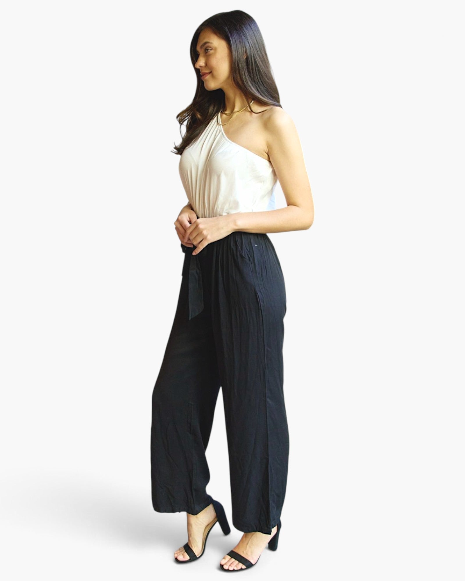 Beach Rose Co. white and black one-shoulder jumpsuit with wide-leg pants and a self-tie belt worn by a model.