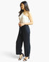 Beach Rose Co. white and black one-shoulder jumpsuit with wide-leg pants and a self-tie belt worn by a model.