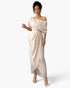 A woman modeling a floor-length off-the-shoulder dress in a light champagne beige satin fabric, set against a plain light gray studio background.
