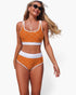 Beach Rose Co. orange polka-dot high-waisted bikini set with white contrast trim worn by a blonde model.
