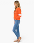 Beach Rose Co. orange sweatshirt with sequin pumpkin and white varsity stripes worn by a model in profile view