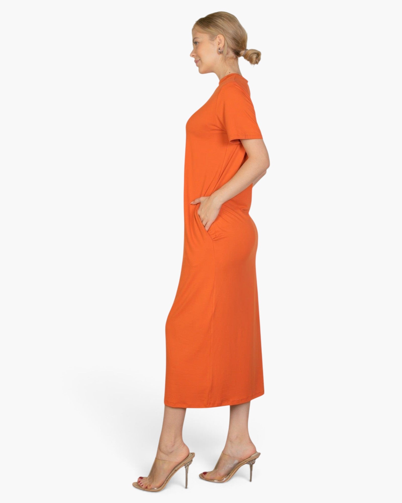 Beach Rose Co. side view of a woman wearing a vibrant orange midi tee dress with functional side pockets