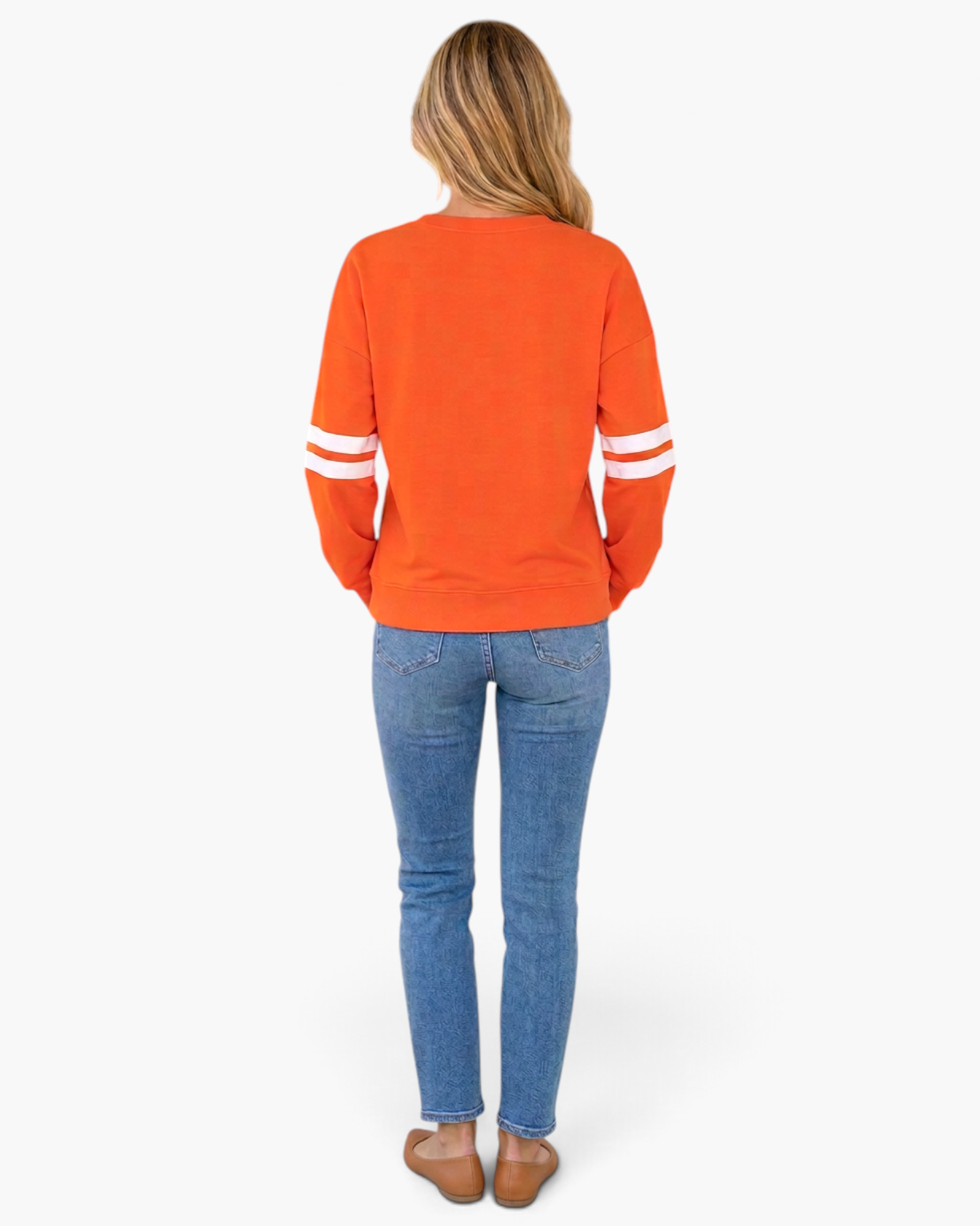 Back view of a woman wearing a Beach Rose Co. orange sweatshirt with white varsity stripes on the sleeves.