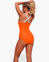 Beach Rose Co. orange and white colorblock one-piece swimsuit with cross-back straps worn by a woman from behind