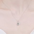 Beach Rose Co. silver oval moissanite halo pendant necklace on a delicate sterling silver chain worn on a neck.